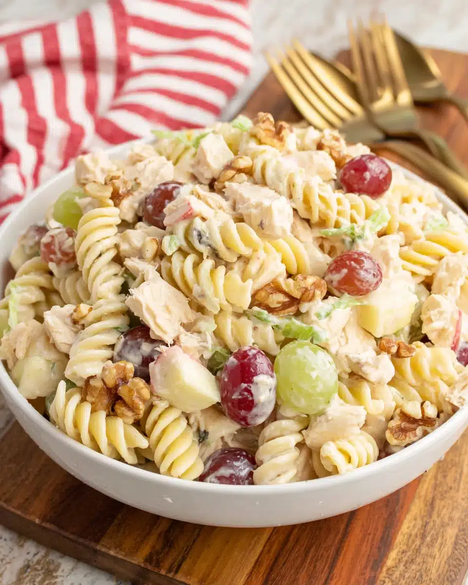 Waldorf chicken pasta salad with rotini, chicken, grapes, apples, and walnuts in a white bowl