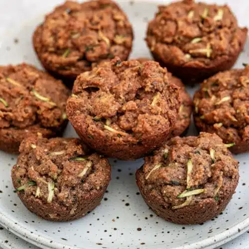Baby zucchini muffins dairy free on a plate with green glass in background