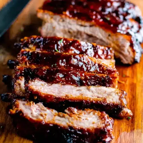 BBQ Baby Back Ribs: The Ultimate Indulgence 1 Sliced BBQ baby back ribs on a wooden board with a glossy sauce