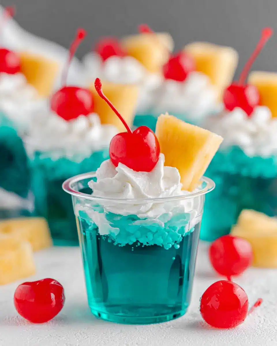 Blue Hawaiian jello shots with whipped cream, pineapple, and cherries