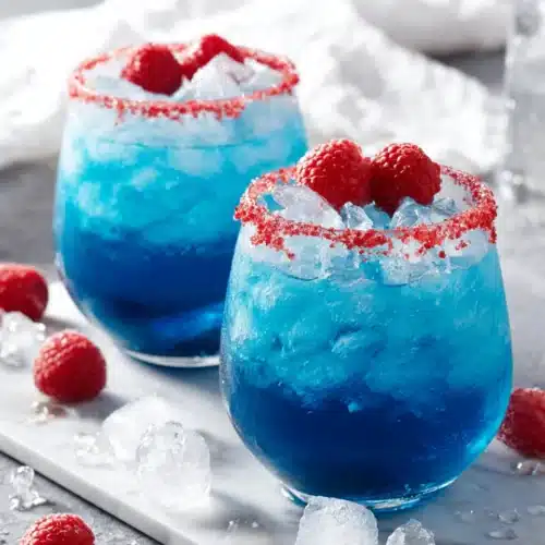 Blue Hawaiian Lemonade Punch in glasses with raspberry garnish and ice