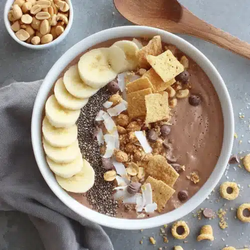 Chocolate peanut butter banana smoothie bowl with banana slices, chia seeds, and cereal toppings