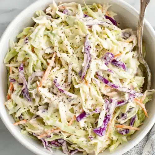 Creamy coleslaw with shredded cabbage and carrots in a white bowl
