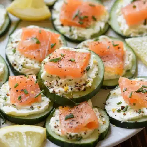 Cucumber smoked salmon bites with cream cheese, chives, and lemon on a plate