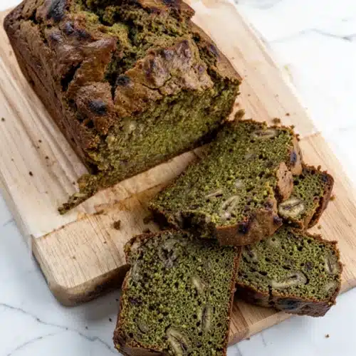 Sliced delicious matcha banana bread on a wooden board, showcasing moist green interior