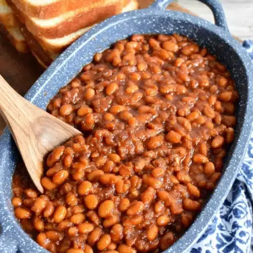 Easy baked beans in a blue speckled dish with wooden spoon