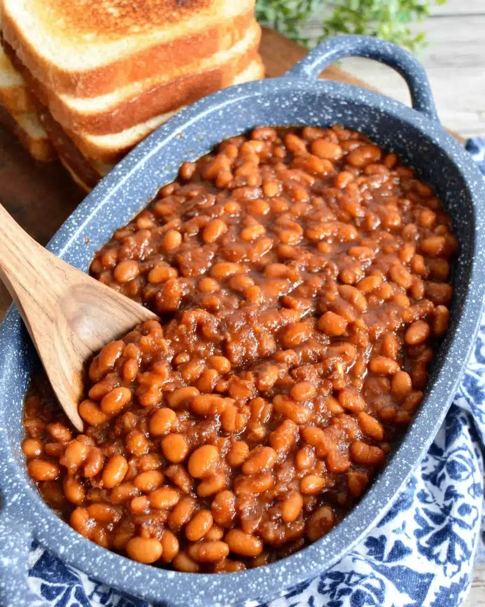 Easy baked beans in a blue speckled dish with wooden spoon