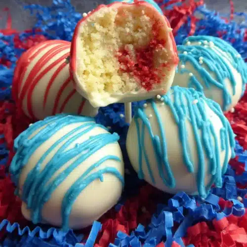Red, white, and blue Fourth of July cake pops with drizzled icing and shredded paper base