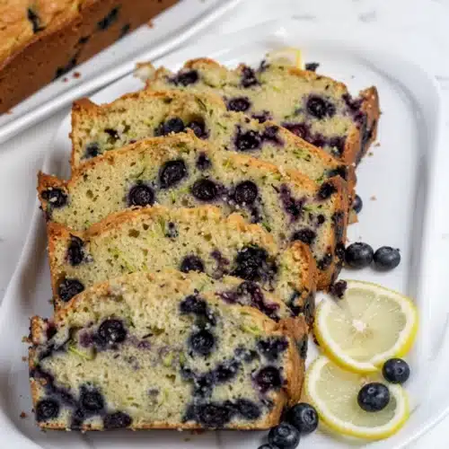 Slices of lemon blueberry zucchini bread with fresh blueberries and lemon garnish