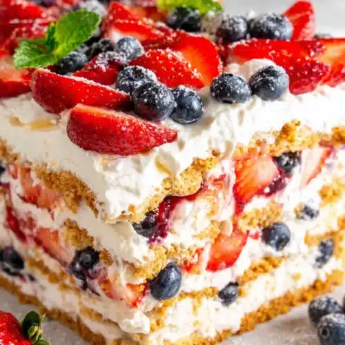 No bake berry icebox cake with layers of graham crackers, cream, strawberries, and blueberries