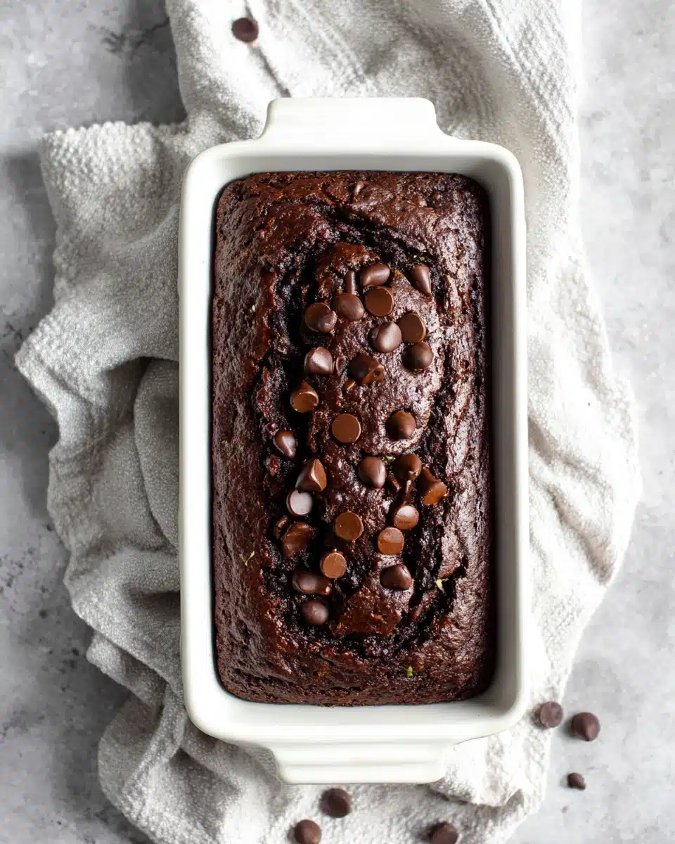 One bowl gluten free chocolate zucchini bread in a white loaf pan with chocolate chips on top