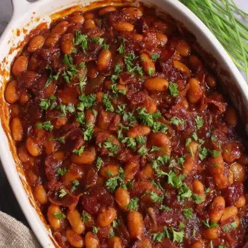 Paula Deen baked beans in a white dish with bacon and herbs