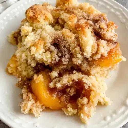 Peach cobbler with frozen peaches and cake mix on a white plate