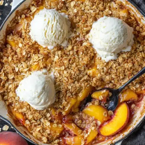 Delicious Peach Crisp Recipe with Fresh Peaches 1 Peach crisp with fresh peaches and vanilla ice cream in a cast iron skillet