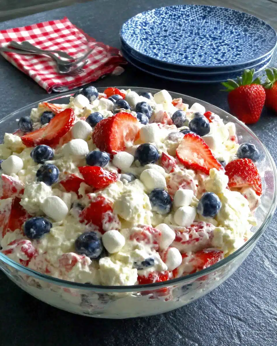 Red, white & blue cheesecake salad with strawberries, blueberries, and marshmallows in a glass dish