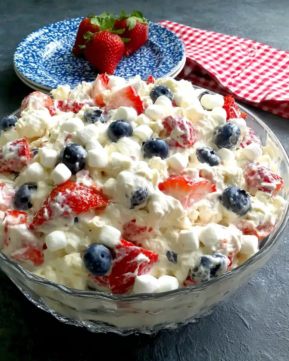 Red, white & blue cheesecake salad with strawberries, blueberries, and marshmallows in a glass dish