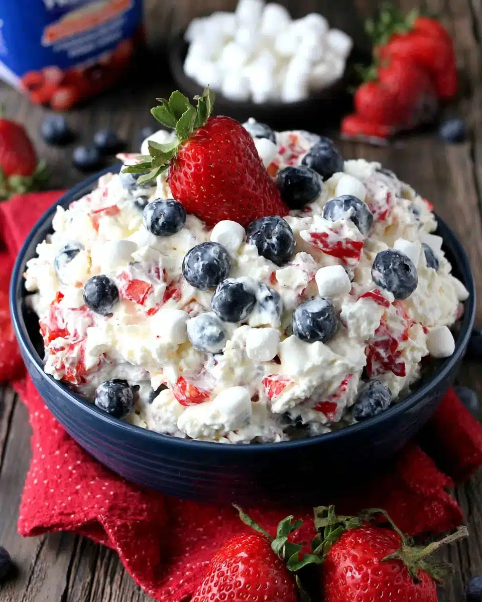 Red white & blue fluff salad with strawberries and blueberries in a blue bowl