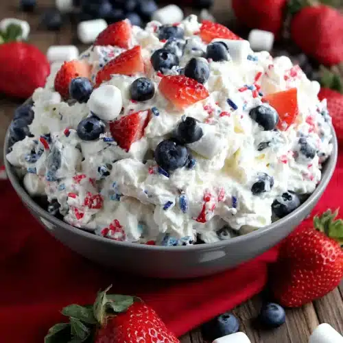 Red white & blue fluff salad with fresh strawberries and blueberries in a blue bowl