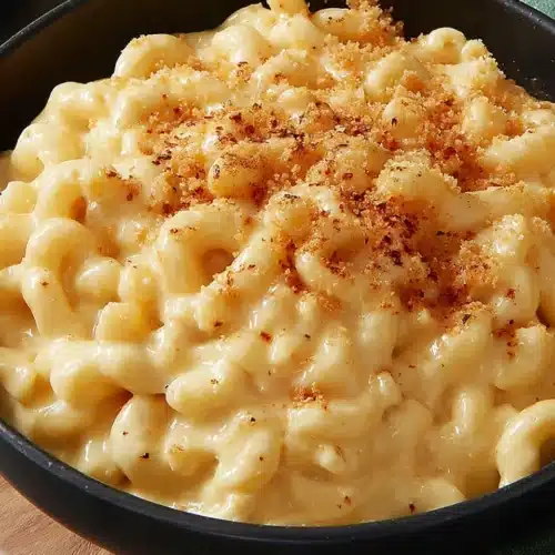Creamy slow cooker macaroni and cheese in a black bowl, topped with breadcrumbs