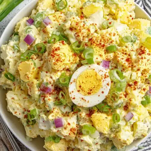 Creamy southern potato salad with eggs, celery, and green onions in a white bowl