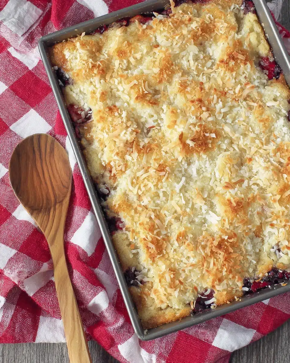 Strawberry blueberry gluten free dump cake with toasted coconut topping in a baking pan