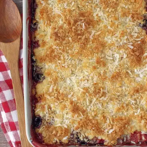Strawberry blueberry gluten free dump cake with toasted coconut topping in a baking pan