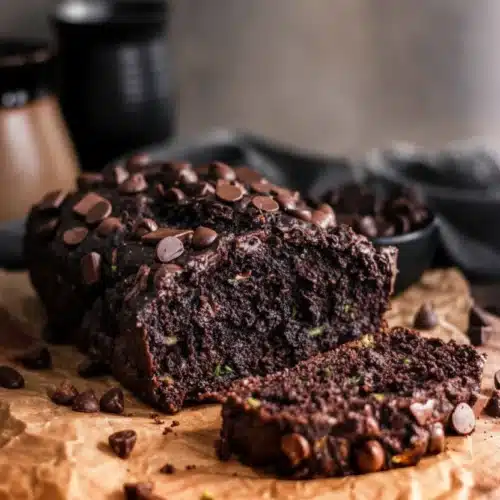 Vegan double chocolate zucchini bread with chocolate chips, sliced and served on parchment paper