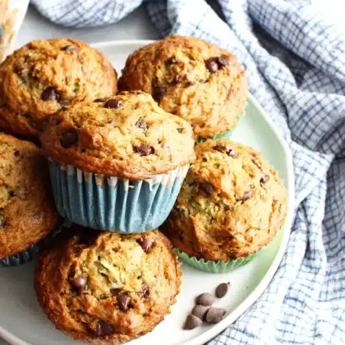 Zucchini banana chocolate chip muffins in blue silicone liners on a plate