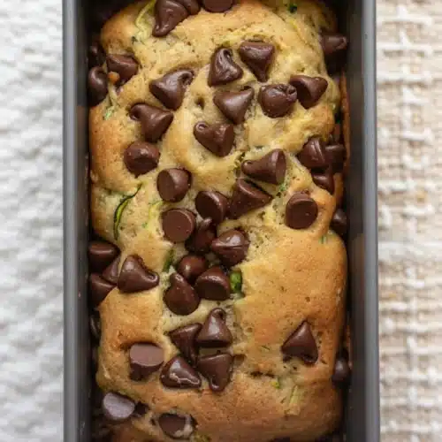 Zucchini bread with chocolate chips in a loaf pan, topped with chocolate chips