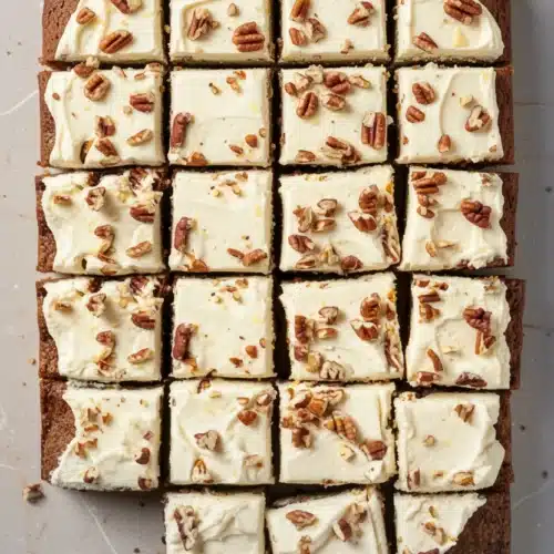 Zucchini cake with lemon cream cheese frosting and pecans, sliced into squares