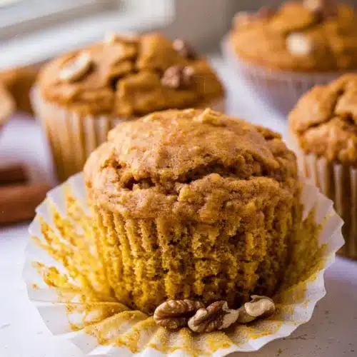 Moist 10-ingredient pumpkin muffin in a white paper liner, golden-brown and fluffy