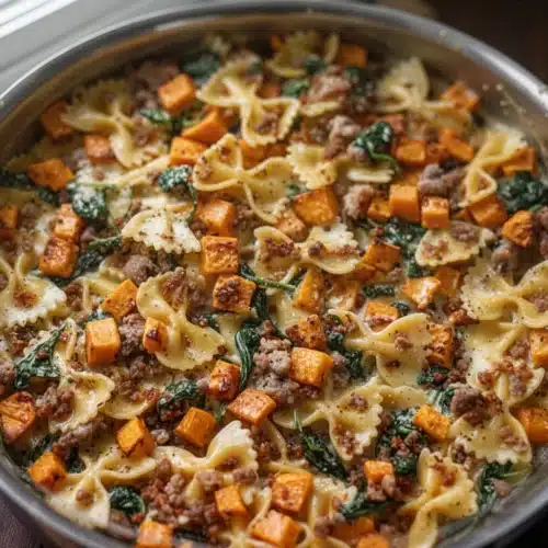 Creamy butternut squash pasta with sausage and spinach in a skillet