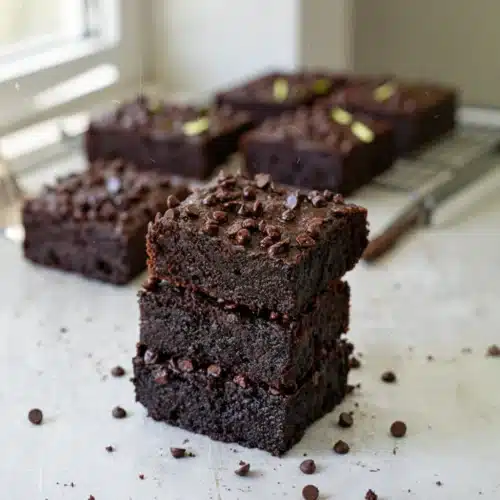 Gesunde Zucchini Brownies: Indulgent and Guilt-Free! 2 Gesunde zucchini brownies stacked with chocolate chips on parchment paper