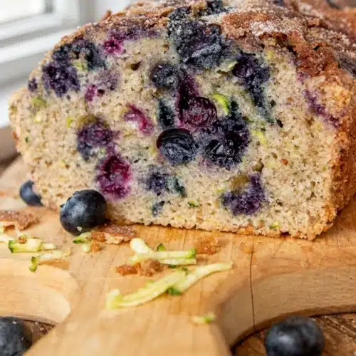 Delicious Gluten Free Zucchini Blueberry Bread Recipe 2 Gluten free zucchini blueberry bread slice with blueberries and zucchini on wooden board