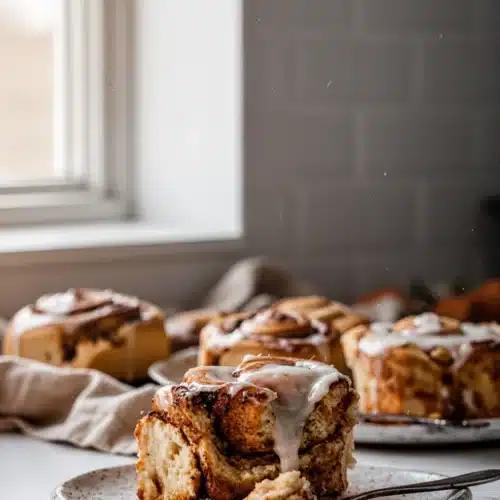 Homemade fall breakfast roll with cinnamon-sugar filling and white frosting on a plate