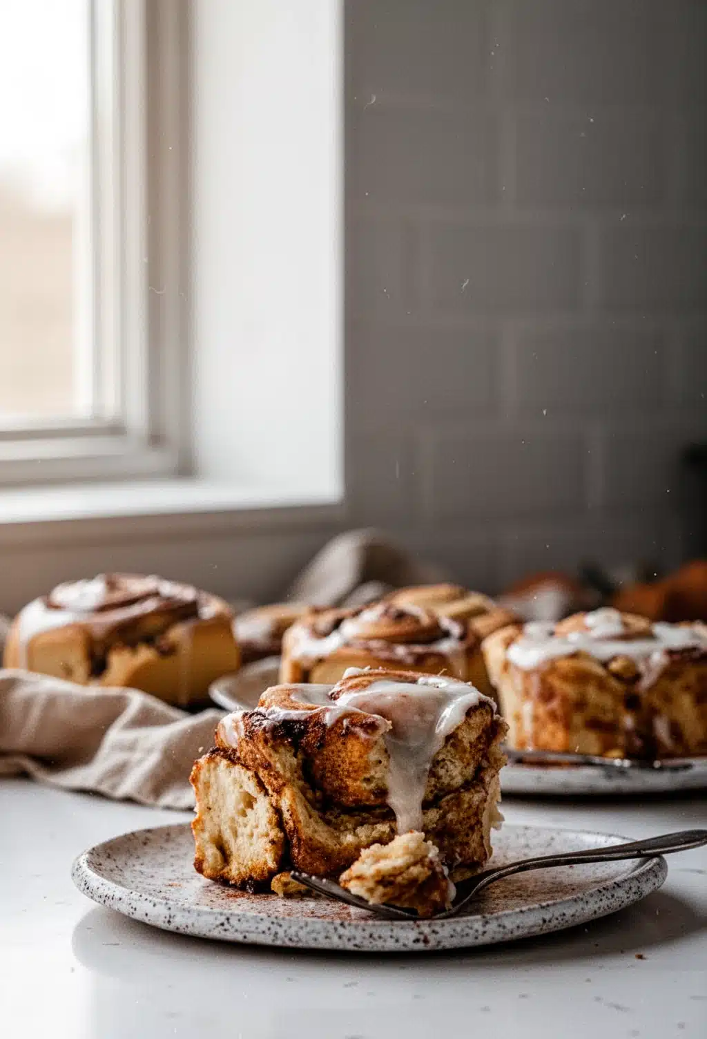 Homemade fall breakfast roll with cinnamon-sugar filling and white frosting on a plate