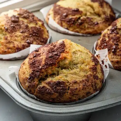 Sticky Oaty Zucchini Cookies: A Delicious Treat 2 Sticky oaty zucchini cookies in a muffin tin with chocolate chunks and flaky salt